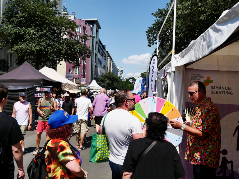 Stand mit Glücksrad und vielen Menschen Stand mit Glücksrad und vielen Menschen