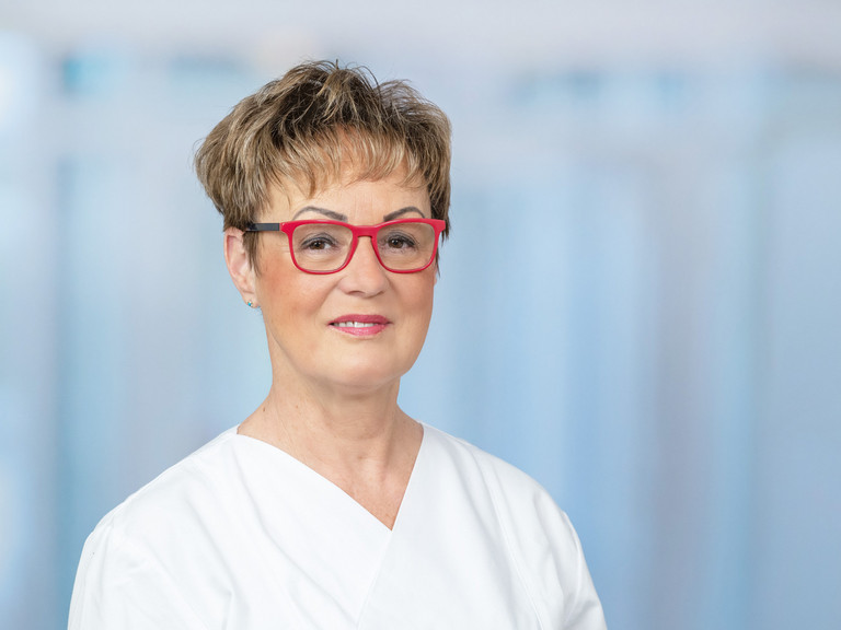 Portraitfoto vor grau-blauem Hintergrund von Marion Baldy, Leitende Hygienefachkraft für die Krankenhäuser und Pflegeeinrichtungen der Immanuel Albertinen Diakonie in Berlin und Brandenburg Portraitfoto vor grau-blauem Hintergrund von Marion Baldy, Leitende Hygienefachkraft für die Krankenhäuser und Pflegeeinrichtungen der Immanuel Albertinen Diakonie in Berlin und Brandenburg